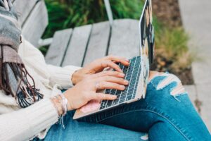 close up of women with laptop on her lap while sitting on a bench - online reviews - google algorithm.jpg